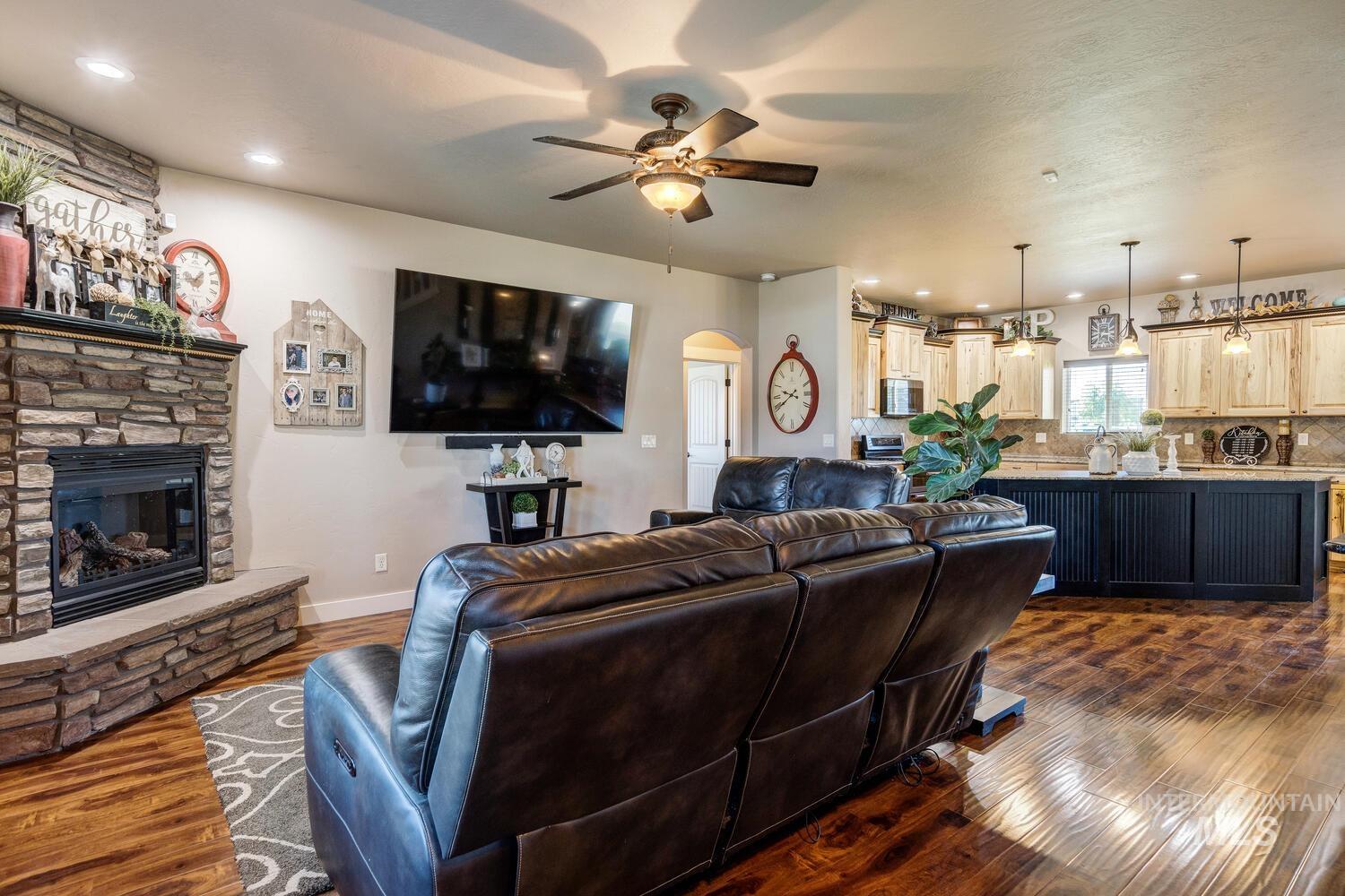 22757 Rosicky Way Caldwell, ID 83607 - Photo 9 of 50 Living area featuring recessed lighting, dark wood finished floors, ceiling fan, arched walkways, and a stone fireplace