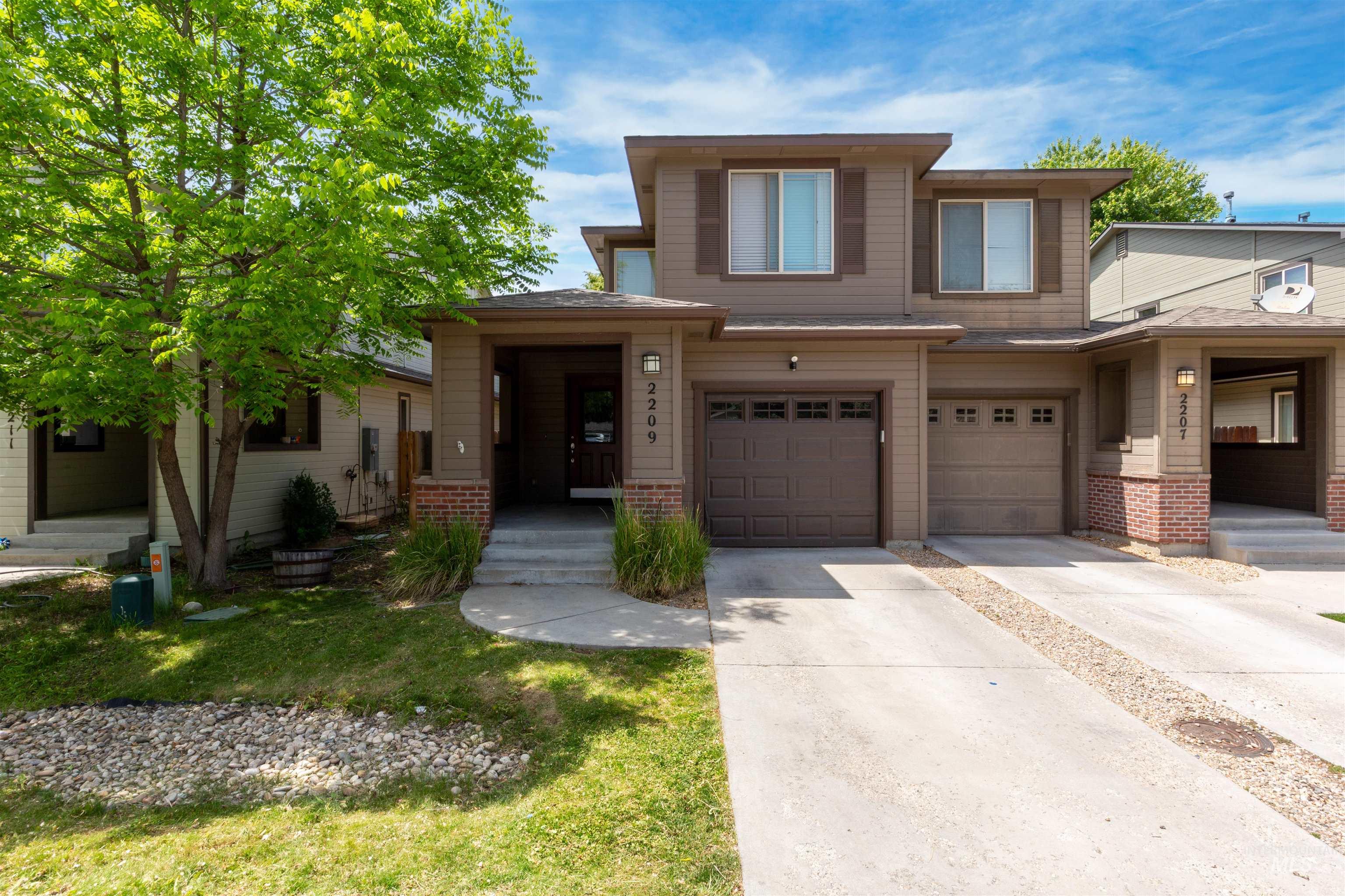 View of front of property featuring driveway, brick siding, a garage, and a front lawn