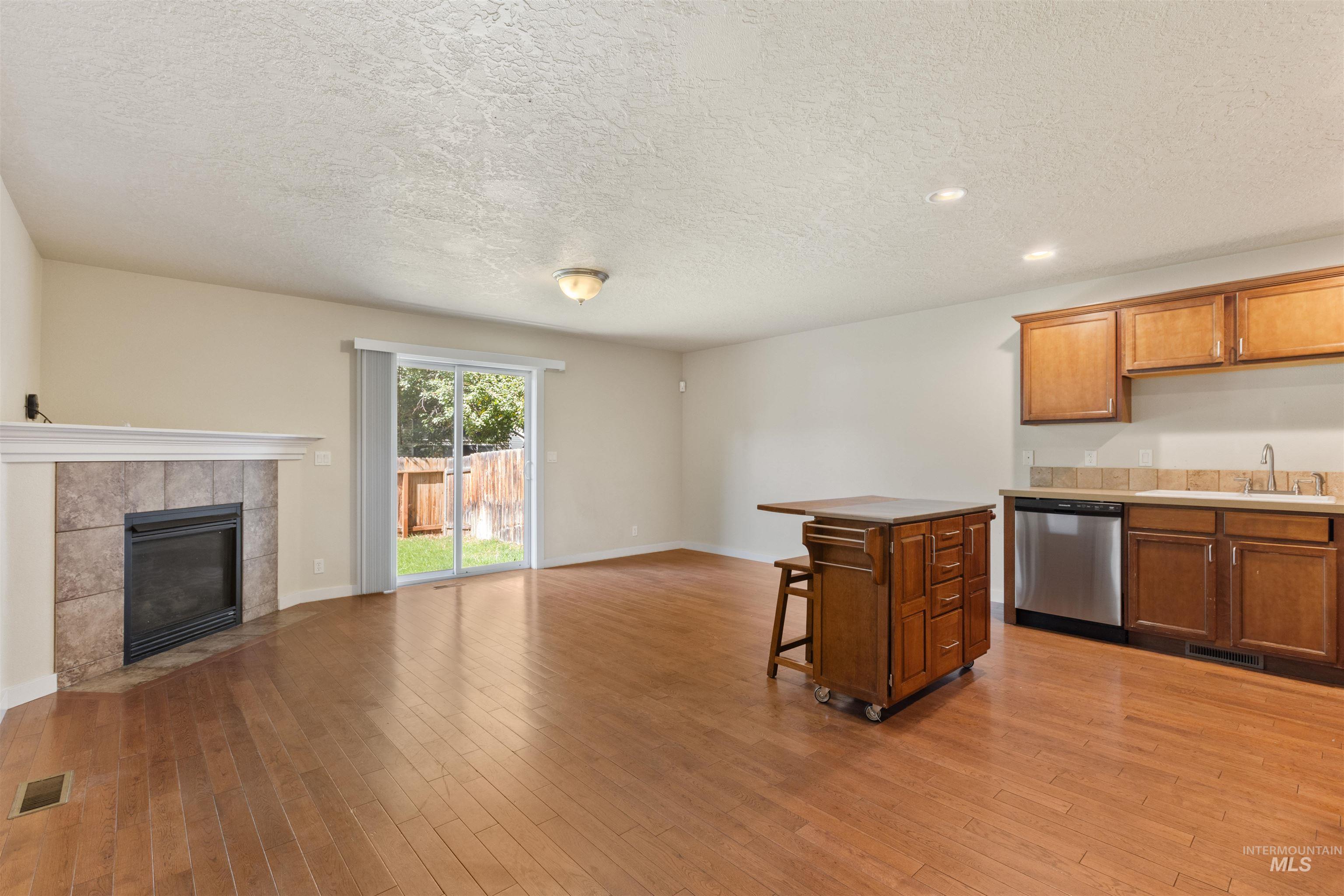 2209 South Amy Avenue Boise, ID 83706 - Photo 30 of 30 Kitchen with a fireplace, open floor plan, a breakfast bar area, a textured ceiling, and brown cabinets