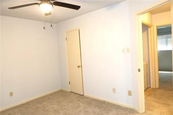 an empty room with a window and ceiling fan