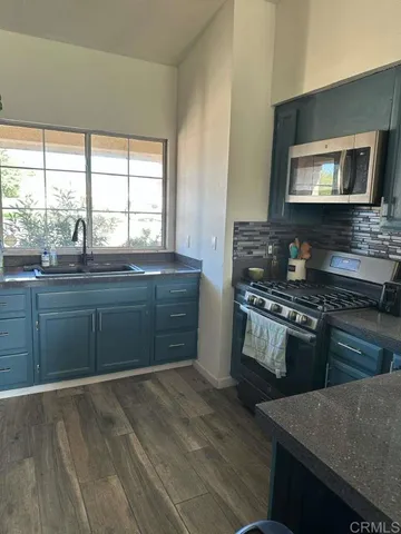 a kitchen with stainless steel appliances granite countertop a stove a sink and a microwave
