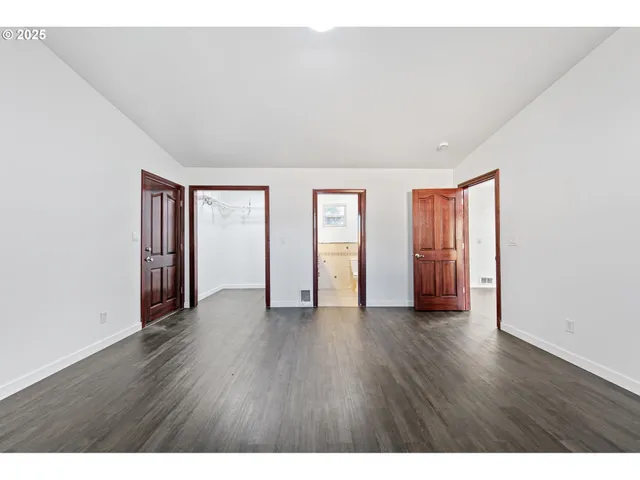 a view of an empty room with wooden floor and windows
