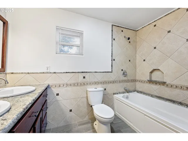 a bathroom with a granite countertop toilet sink and mirror