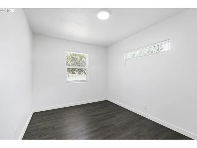 a view of a backyard with large trees and wooden fence
