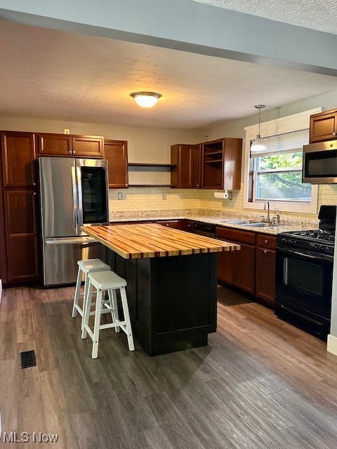 4184 Johnson Road Barberton, OH 44203 - Photo 3 of 25 Kitchen with wooden counters, appliances with stainless steel finishes, a kitchen breakfast bar, dark wood-type flooring, and a textured ceiling