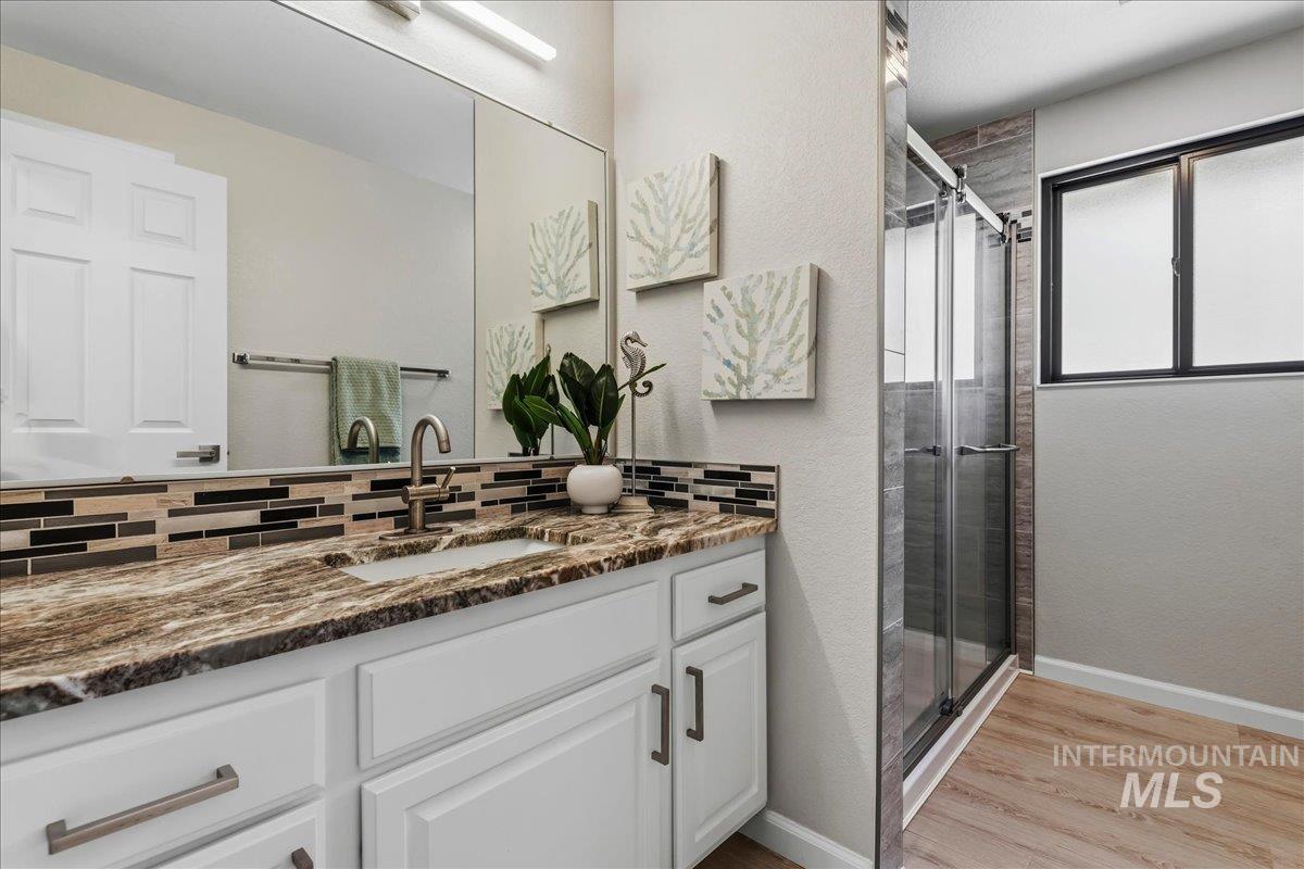 599 Pebble Beach Way Eagle, ID 83616 - Photo 28 of 44 Vanity with a brown-toned countertop, under-mount sink, and mosaic tile backsplash