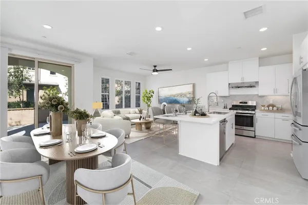 a kitchen with a dining table wooden floor and stainless steel appliances