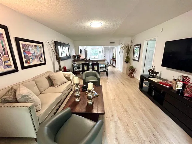 a living room with furniture a flat screen tv and kitchen view