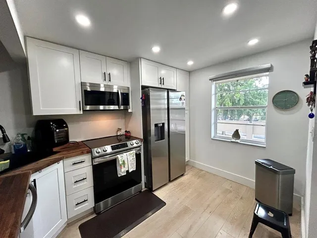 a kitchen with stainless steel appliances granite countertop a stove a refrigerator a sink a stove with wooden floors