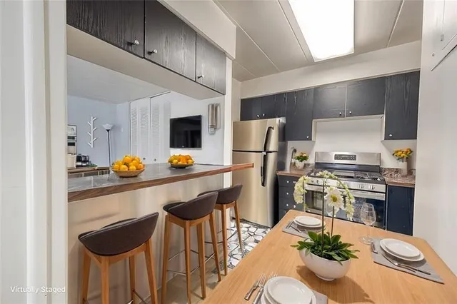 a kitchen with stainless steel appliances kitchen island granite countertop a table chairs stove and refrigerator