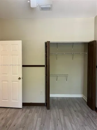 a view of a hallway with wooden floor and a refrigerator