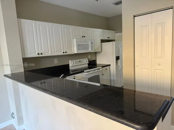 a kitchen with granite countertop white cabinets and white appliances