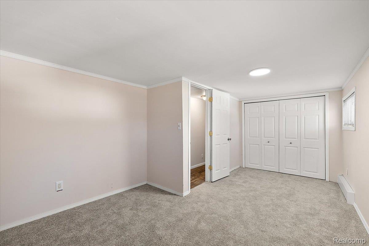 4705 Ketchum Road St. Clair, MI 48079 - Photo 43 of 58 Unfurnished bedroom with ornamental molding, light carpet, a baseboard radiator, and a closet