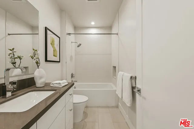 a bathroom with a granite countertop sink a toilet a mirror a vanity and shower
