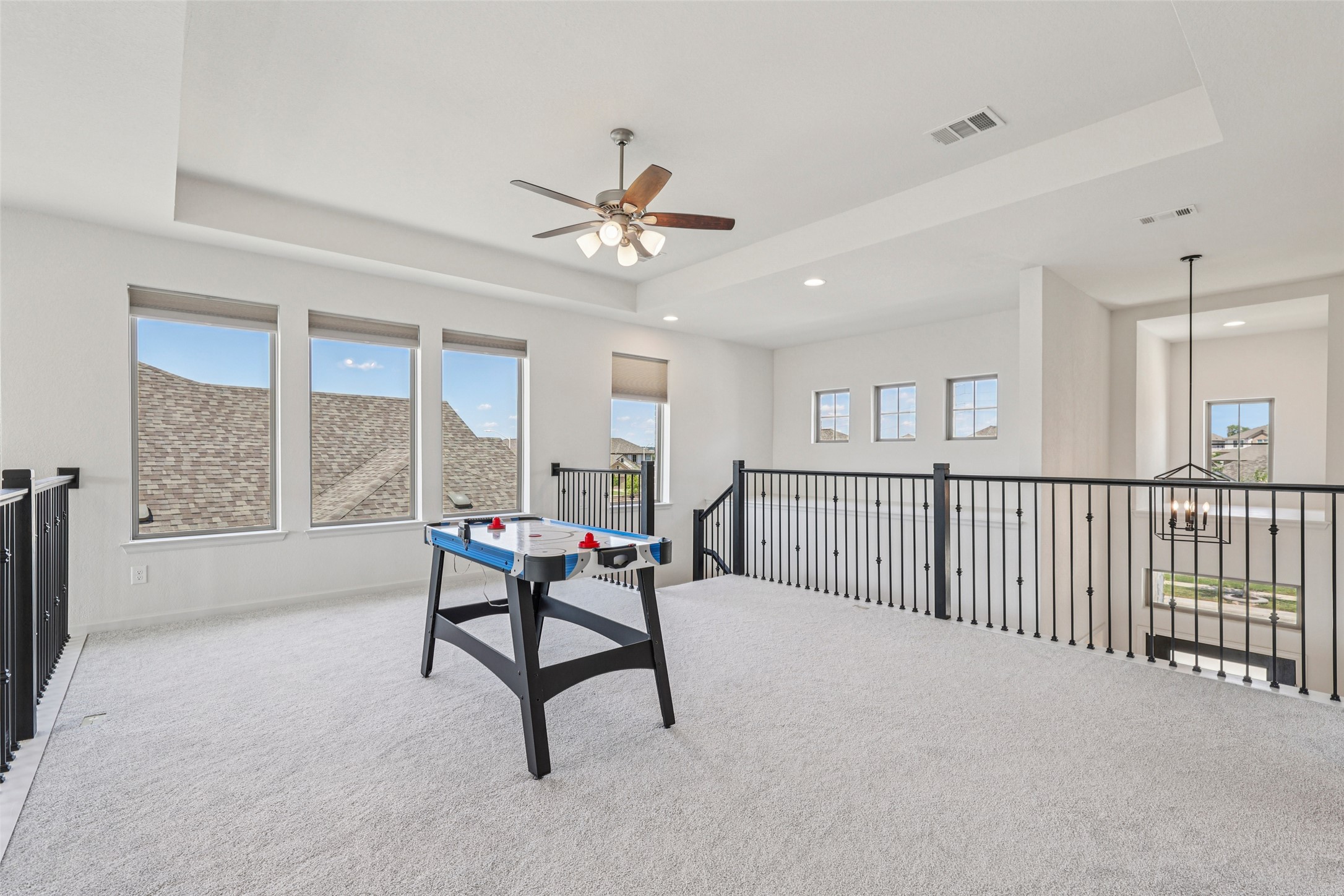 1140 Bryson Rdg Trail Leander, TX 78641 - Photo 25 of 39 Expansive loft area featuring light-colored carpeting, multiple windows providing natural light, and a ceiling fan
