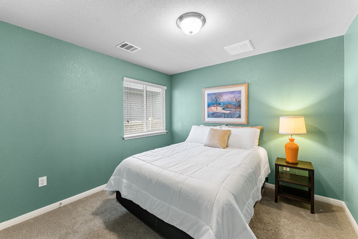 408 Cane River Road Pflugerville, TX 78660 - Photo 23 of 38 a bedroom with a bed and a night stand