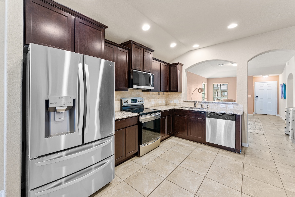 408 Cane River Road Pflugerville, TX 78660 - Photo 3 of 38 a large kitchen with stainless steel appliances granite countertop a refrigerator and a sink