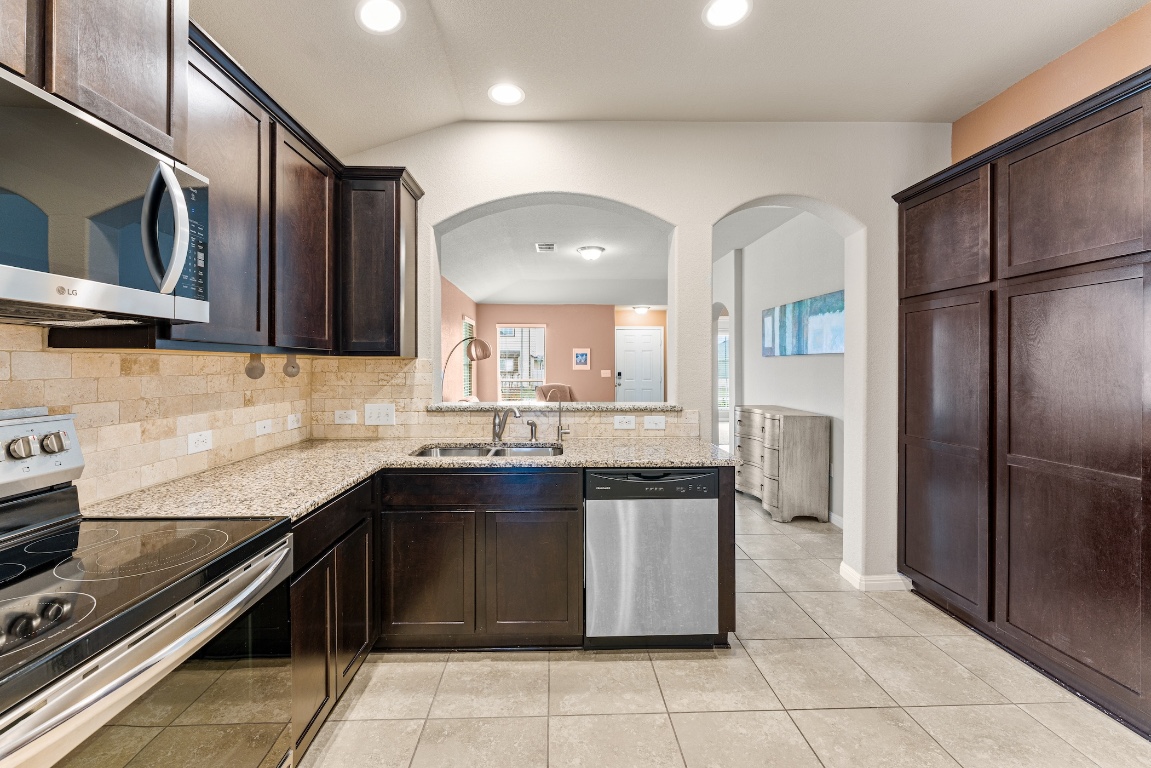 408 Cane River Road Pflugerville, TX 78660 - Photo 4 of 38 a kitchen with stainless steel appliances granite countertop a sink and a refrigerator