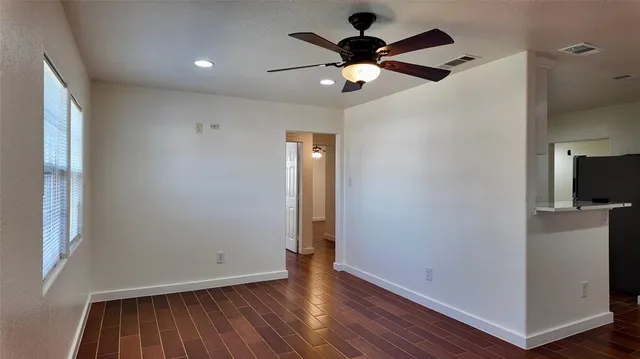 an empty room with wooden floor and a ceiling fan