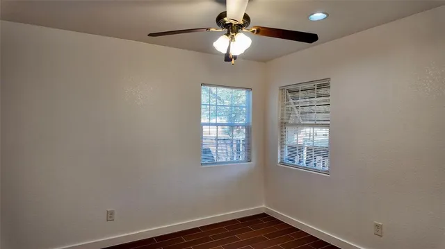 a view of an empty room with window and wooden floor