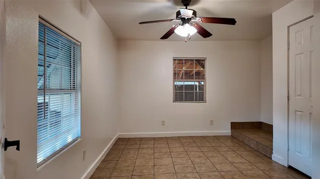 a view of an empty room with a ceiling fan and window