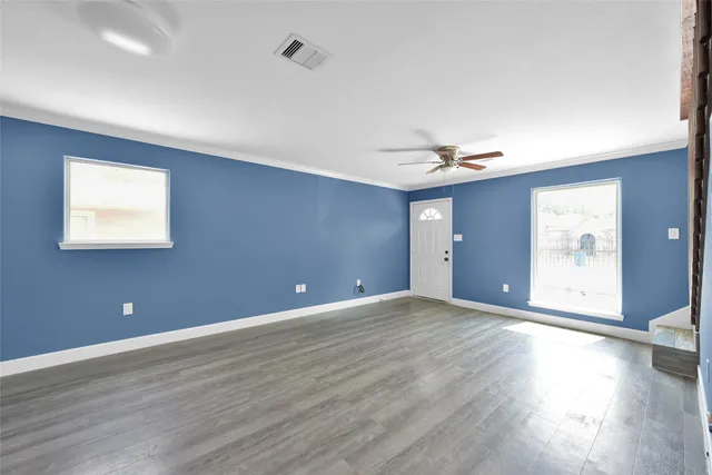 an empty room with wooden floor and windows