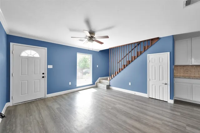 a view of an empty room with window and wooden floor