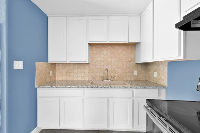 a kitchen with granite countertop white cabinets and a stainless steel appliances