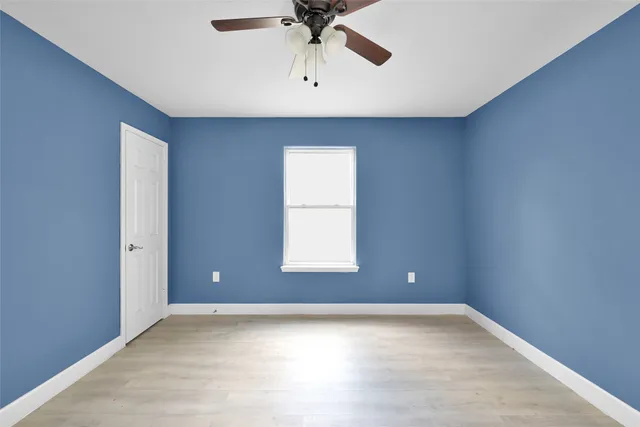 an empty room with a window and a ceiling fan