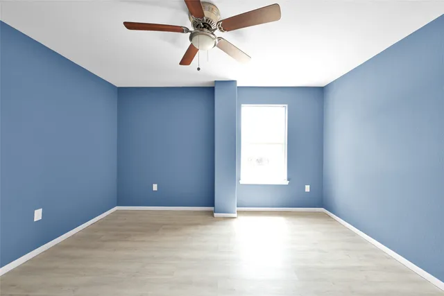 an empty room with a window and a fan
