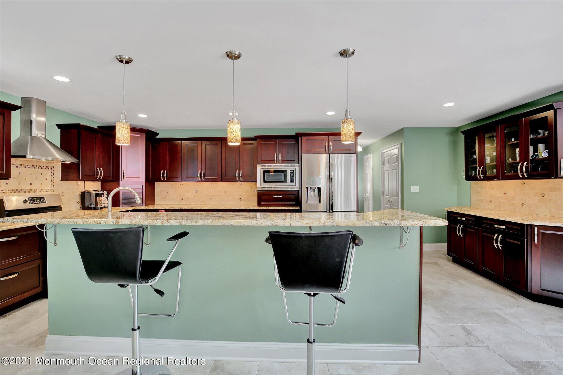 76 Swimming River Road Lincroft, NJ 07738 - Photo 14 of 50 a kitchen with stainless steel appliances granite countertop a table chairs sink and cabinets