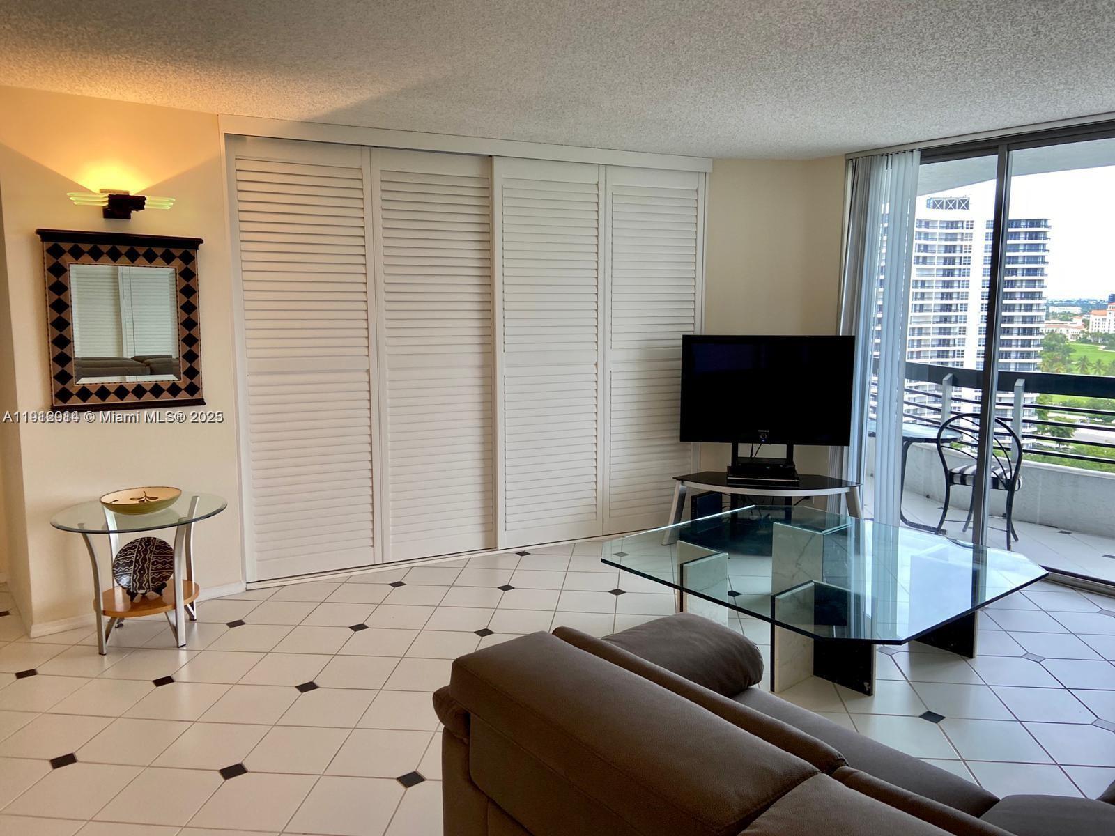 3530 Mystic Pointe Drive, Unit 1708 Aventura, FL 33180 - Photo 4 of 27 a living room with furniture and a flat screen tv