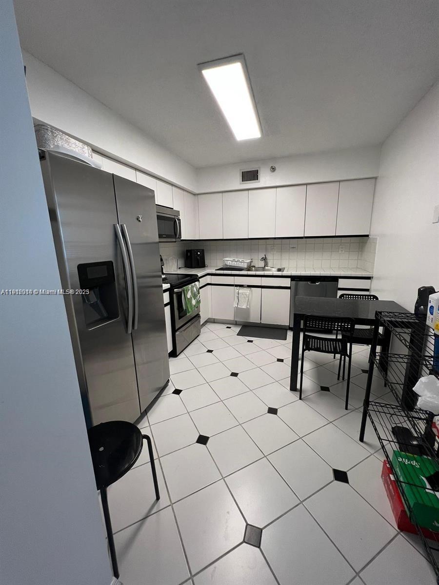 3530 Mystic Pointe Drive, Unit 1708 Aventura, FL 33180 - Photo 7 of 27 a kitchen with stainless steel appliances kitchen island granite countertop a sink and cabinets