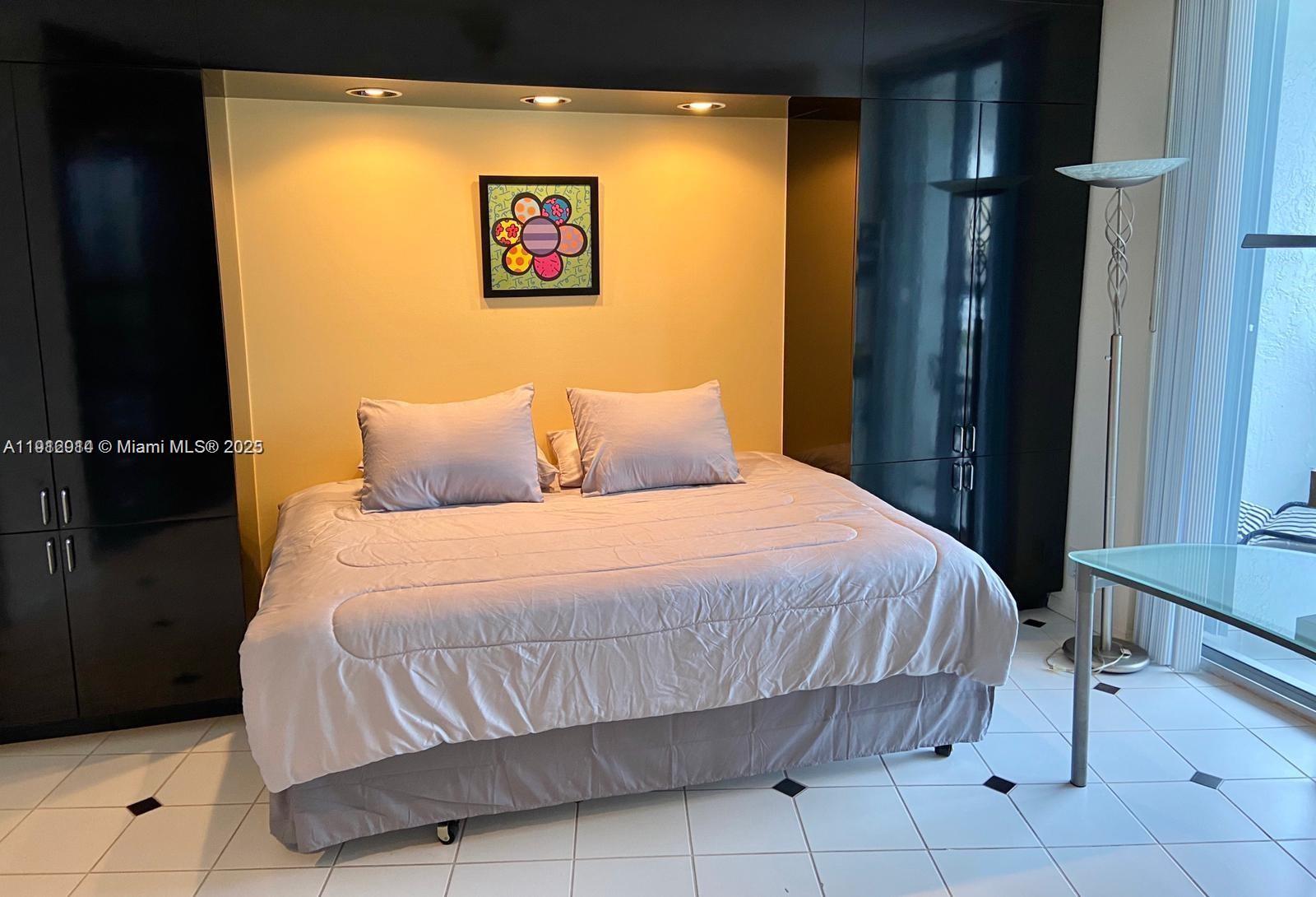 3530 Mystic Pointe Drive, Unit 1708 Aventura, FL 33180 - Photo 9 of 27 a bedroom with a bed and a painting on the wall