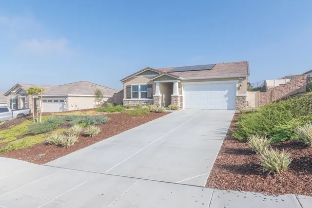 a front view of a house with a yard and potted plants