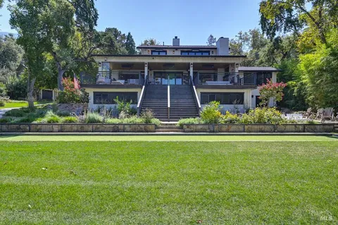 a view of a house with swimming pool and lawn chairs under an umbrella