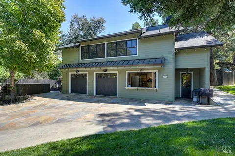 a view of swimming pool with lawn chairs and large trees