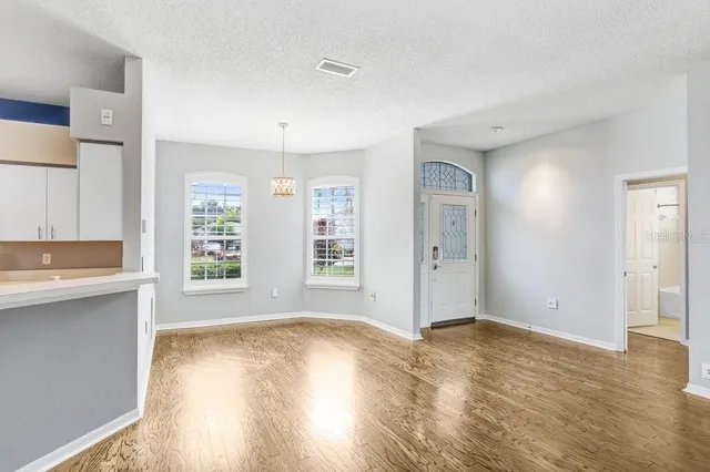 a view of an empty room with window and wooden floor