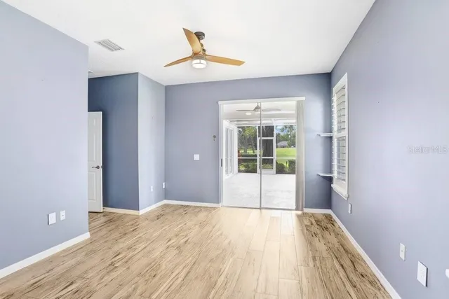 a view of empty room with wooden floor and fan