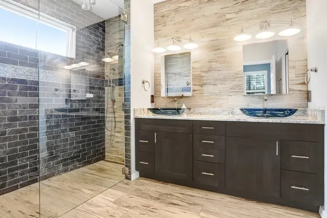 a bathroom with a granite countertop sink a mirror and a shower
