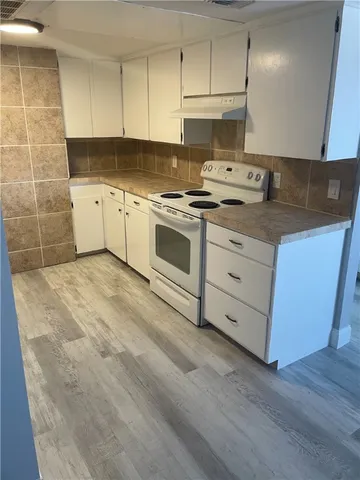 a view of a kitchen with wooden floor and a fireplace