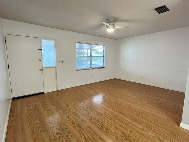 an empty room with wooden floor and windows