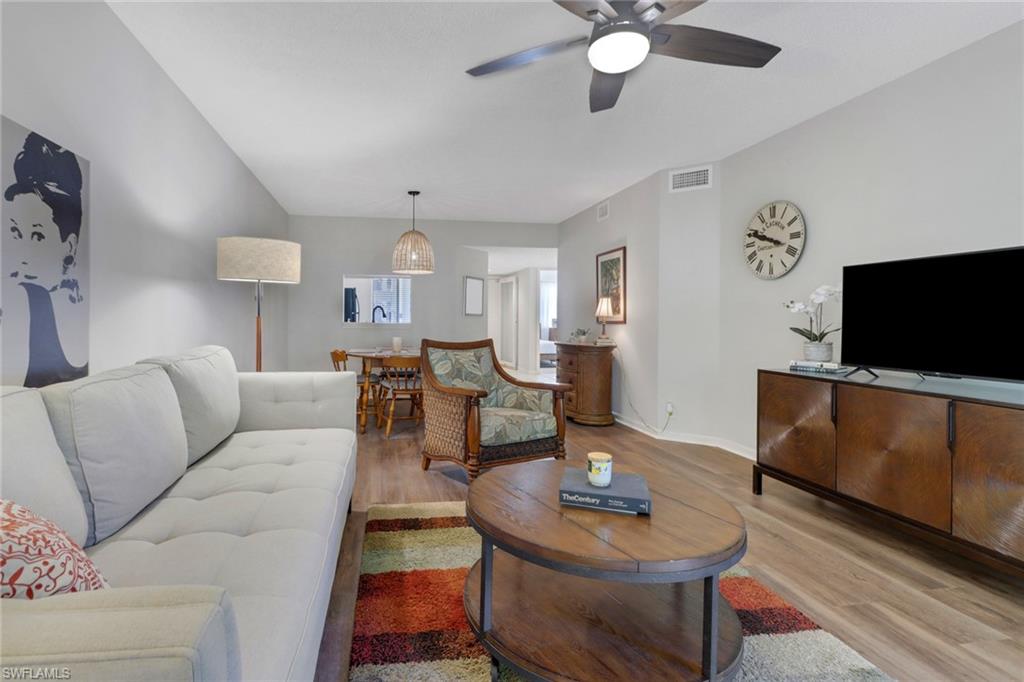 7791 Esmeralda Way, Unit L103 Naples, FL 34109 - Photo 11 of 46 a living room with furniture a flat screen tv and kitchen view