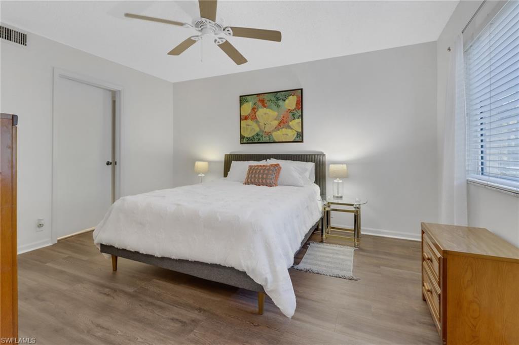 7791 Esmeralda Way, Unit L103 Naples, FL 34109 - Photo 13 of 46 a bedroom with a bed and wooden floor