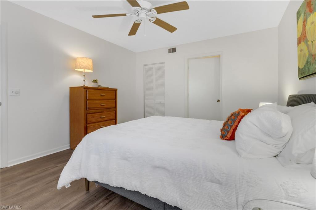7791 Esmeralda Way, Unit L103 Naples, FL 34109 - Photo 14 of 46 a bedroom with a bed and wooden floor