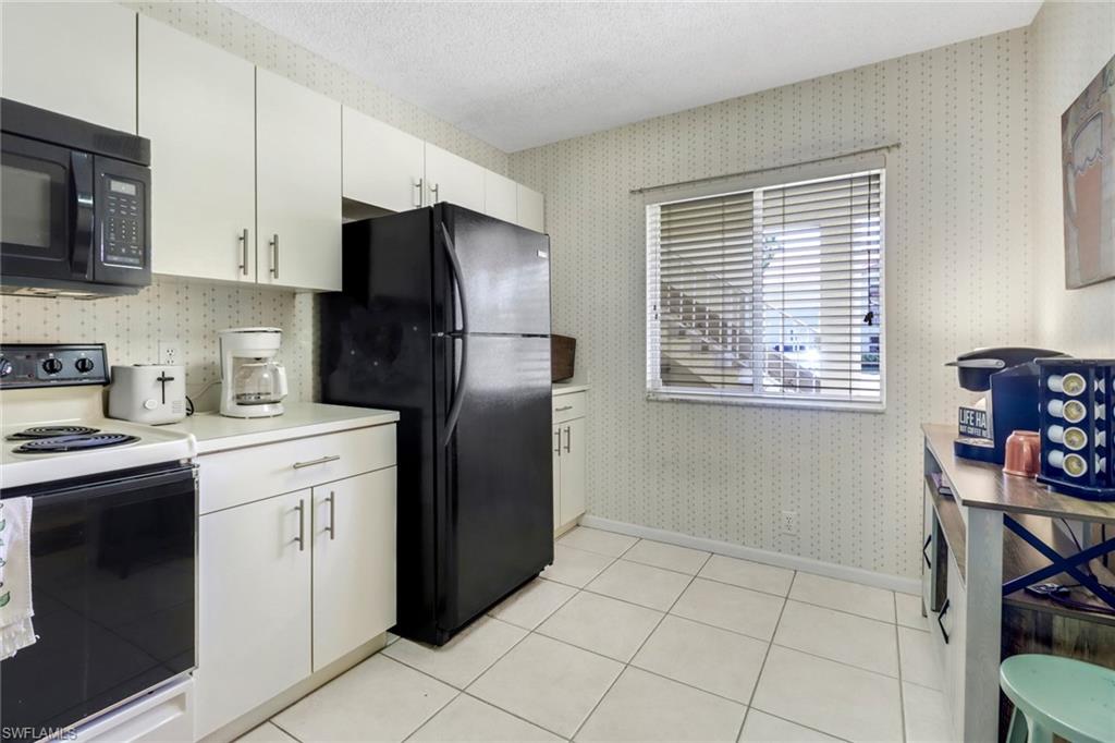 7791 Esmeralda Way, Unit L103 Naples, FL 34109 - Photo 29 of 46 a kitchen with stainless steel appliances a refrigerator sink and microwave