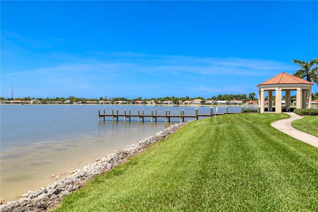7791 Esmeralda Way, Unit L103 Naples, FL 34109 - Photo 41 of 46 a view of a lake with a yard and large trees
