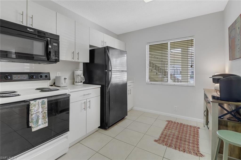 7791 Esmeralda Way, Unit L103 Naples, FL 34109 - Photo 5 of 46 a kitchen with stainless steel appliances granite countertop a stove a sink and a refrigerator