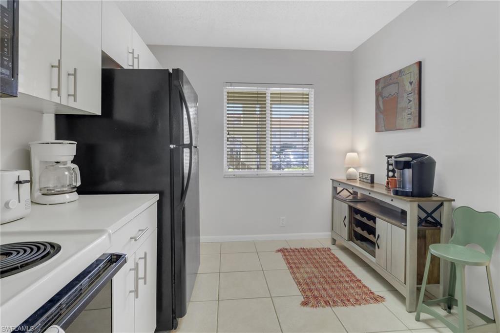 7791 Esmeralda Way, Unit L103 Naples, FL 34109 - Photo 6 of 46 a kitchen with a stove and a refrigerator