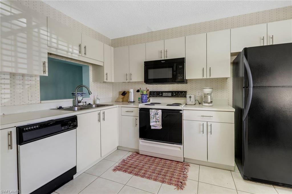 7791 Esmeralda Way, Unit L103 Naples, FL 34109 - Photo 7 of 46 a kitchen with a sink stove and refrigerator